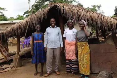 Afrikanische Familie steht vor einer Hütte