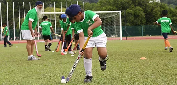 Jungen spielen Hockey im Gras