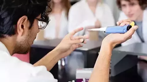 ine Person im Laborkittel arbeitet mit einer Pipette im Labor und konzentriert sich dabei auf das präzise Abmessen.